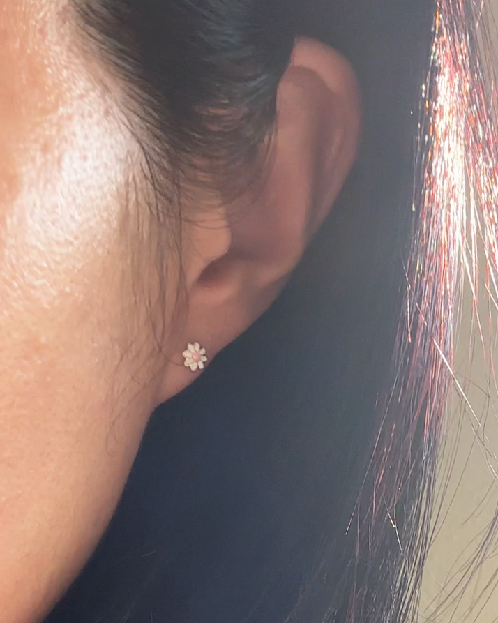Close-up of an ear wearing a small earring with fireworks in the background