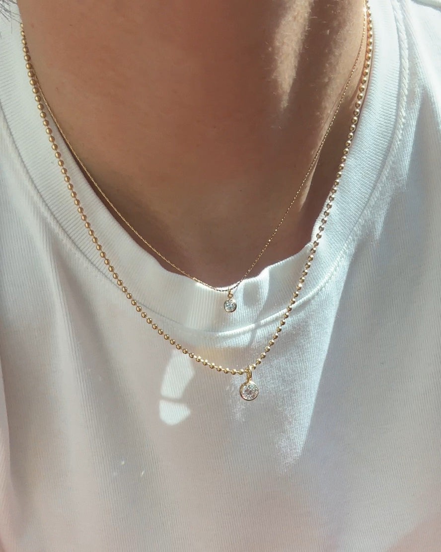 Gold necklace with small round pendants on a white shirt