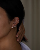 Close-up of a person wearing two diamond stud earrings with a blurred background