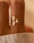 Three gold rings with diamonds on a hand against a neutral background