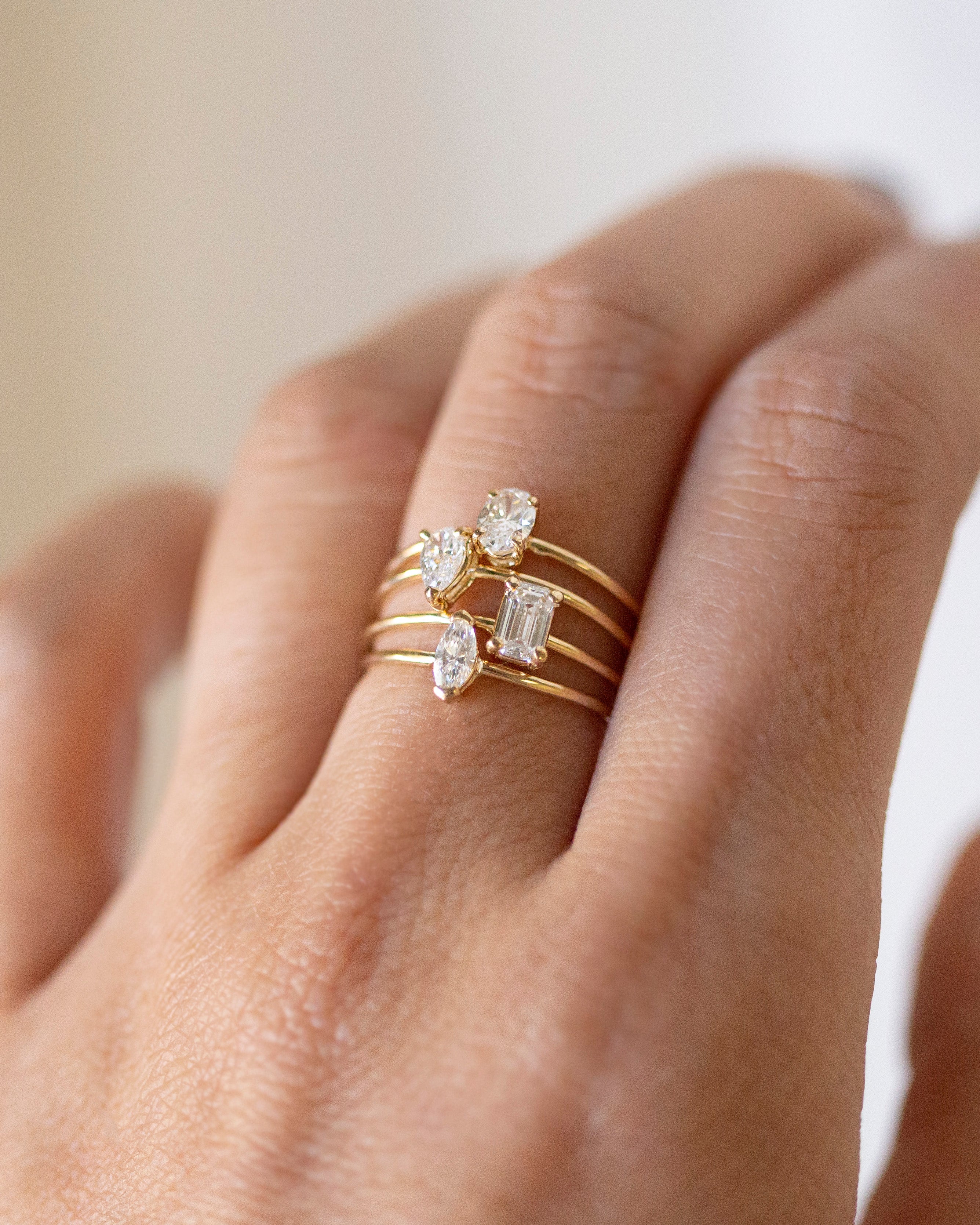 Gold ring with diamond accents on a hand against a neutral background