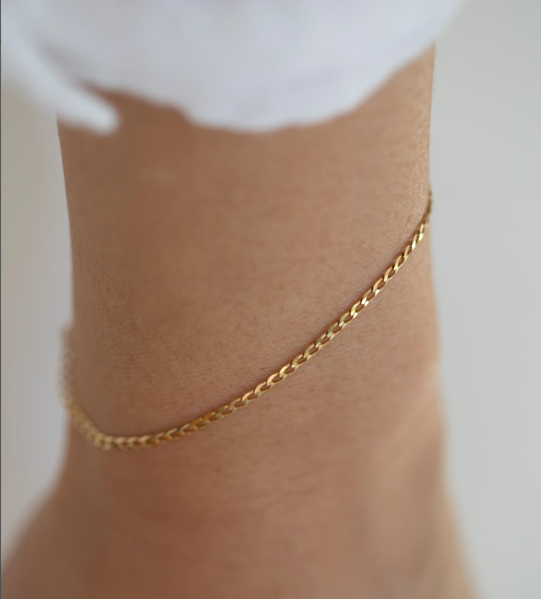 Gold anklet on a person's ankle against a white background