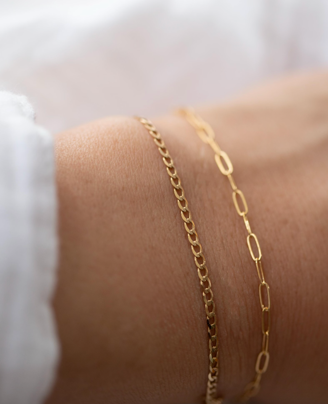 Gold chain bracelet on a wrist with a blurred background