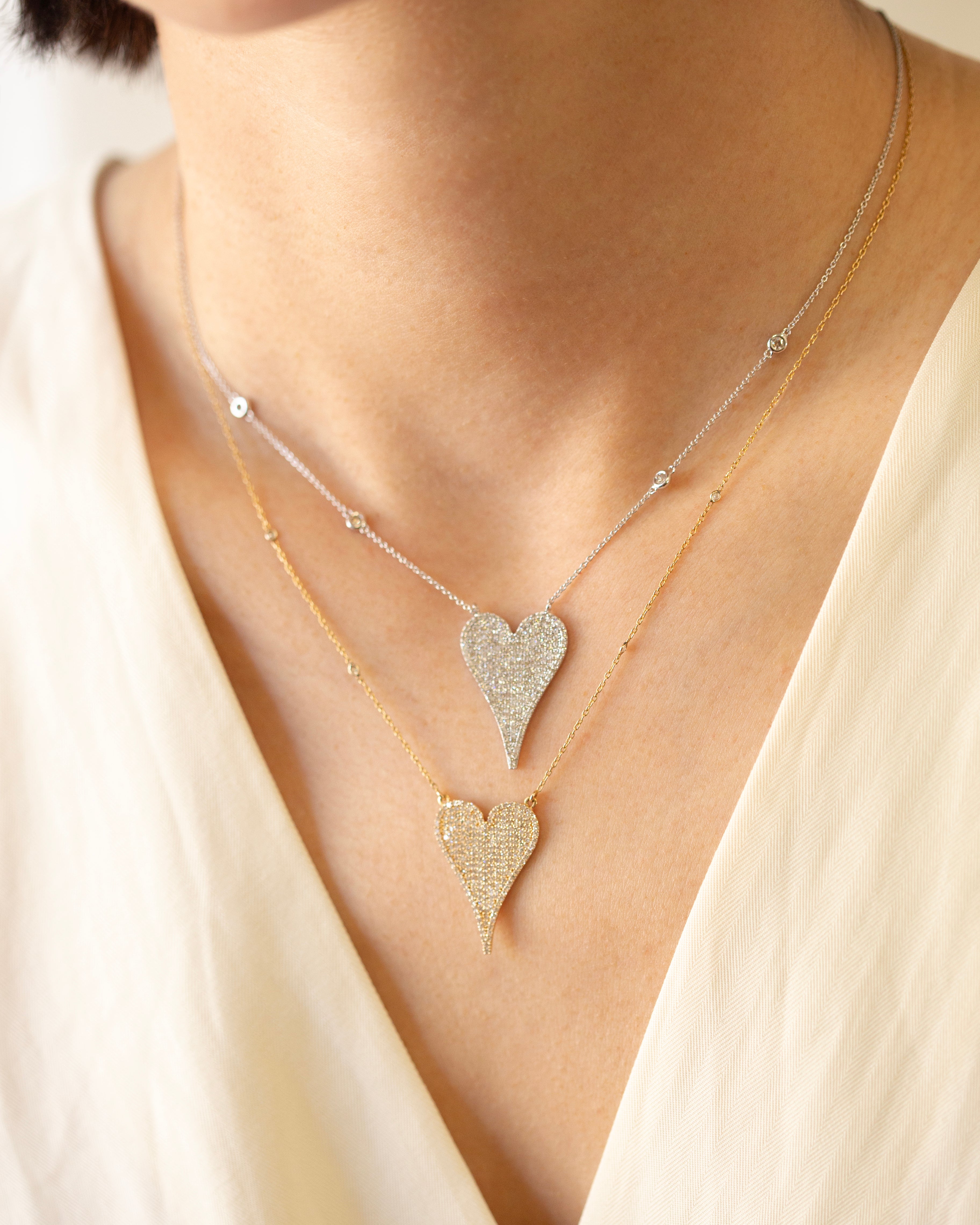 Necklace with heart-shaped pendants on a person wearing a light-colored top.