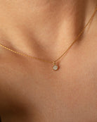 Gold necklace with a small pendant on a person's neck