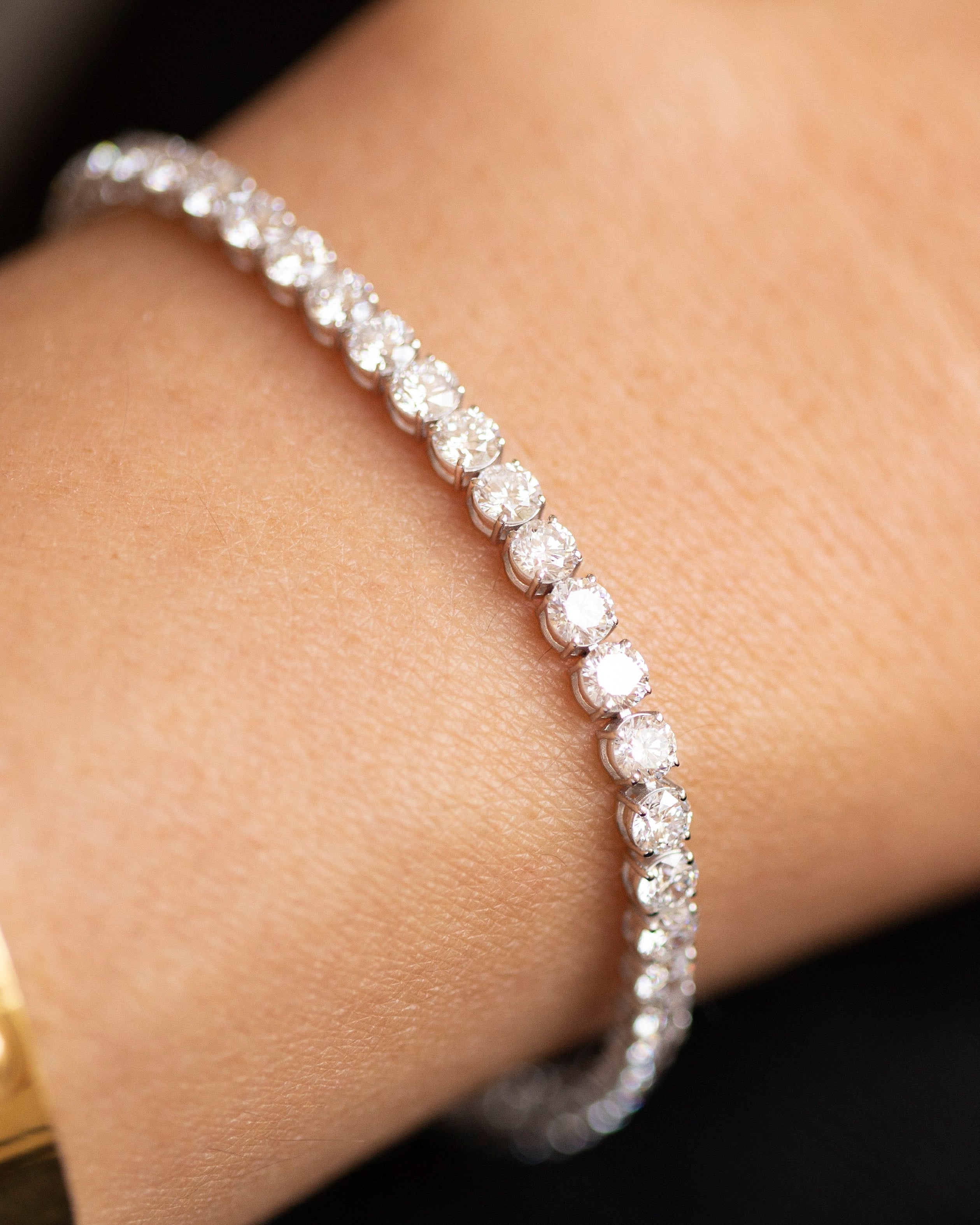 Diamond bracelet on a wrist with a gold watch, close-up view.