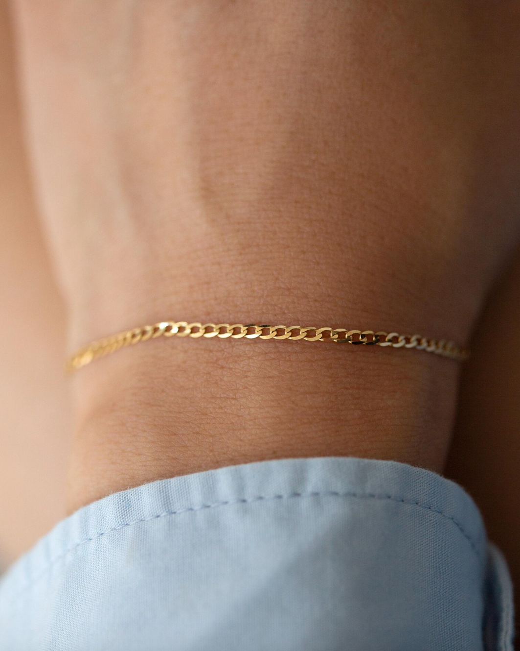 Gold bracelet on a wrist with a blurred background