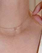 Close-up of a delicate necklace being worn on a person's neck.