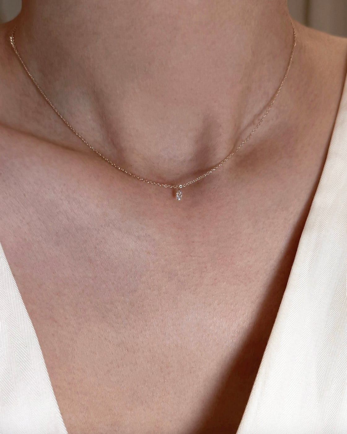 yellow gold necklace with a small diamond pendant on a neutral background