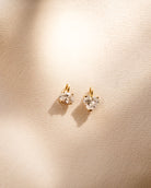 Heart-shaped diamond earrings on a beige background