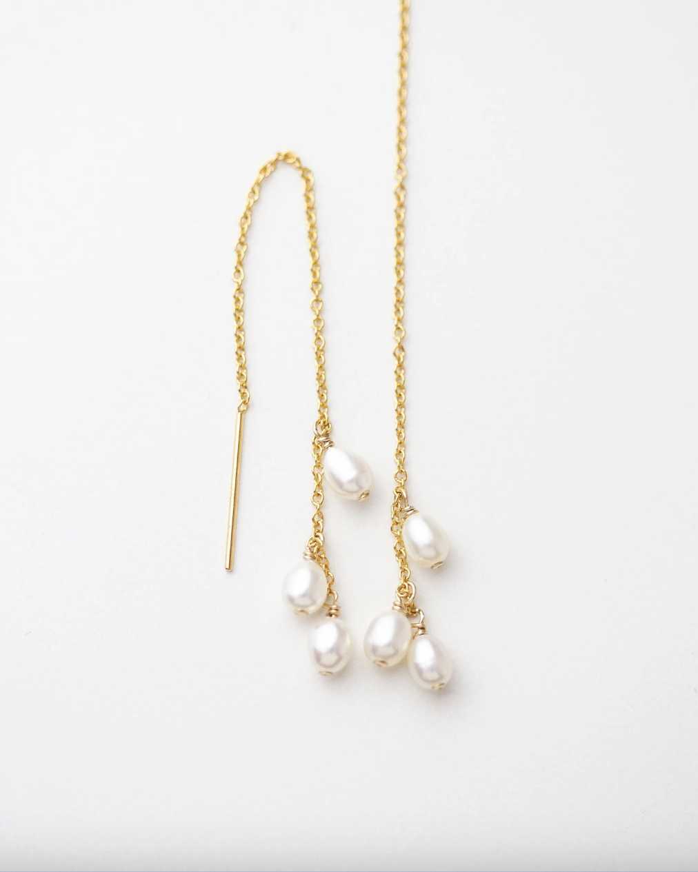 Gold chain earrings with pearl drops on a white background