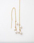 Gold chain earrings with pearl drops on a white background