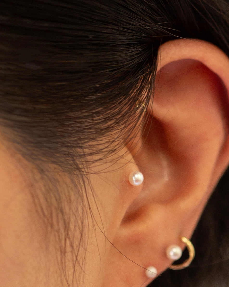 Close-up of an ear wearing pearl earrings with a blurred background