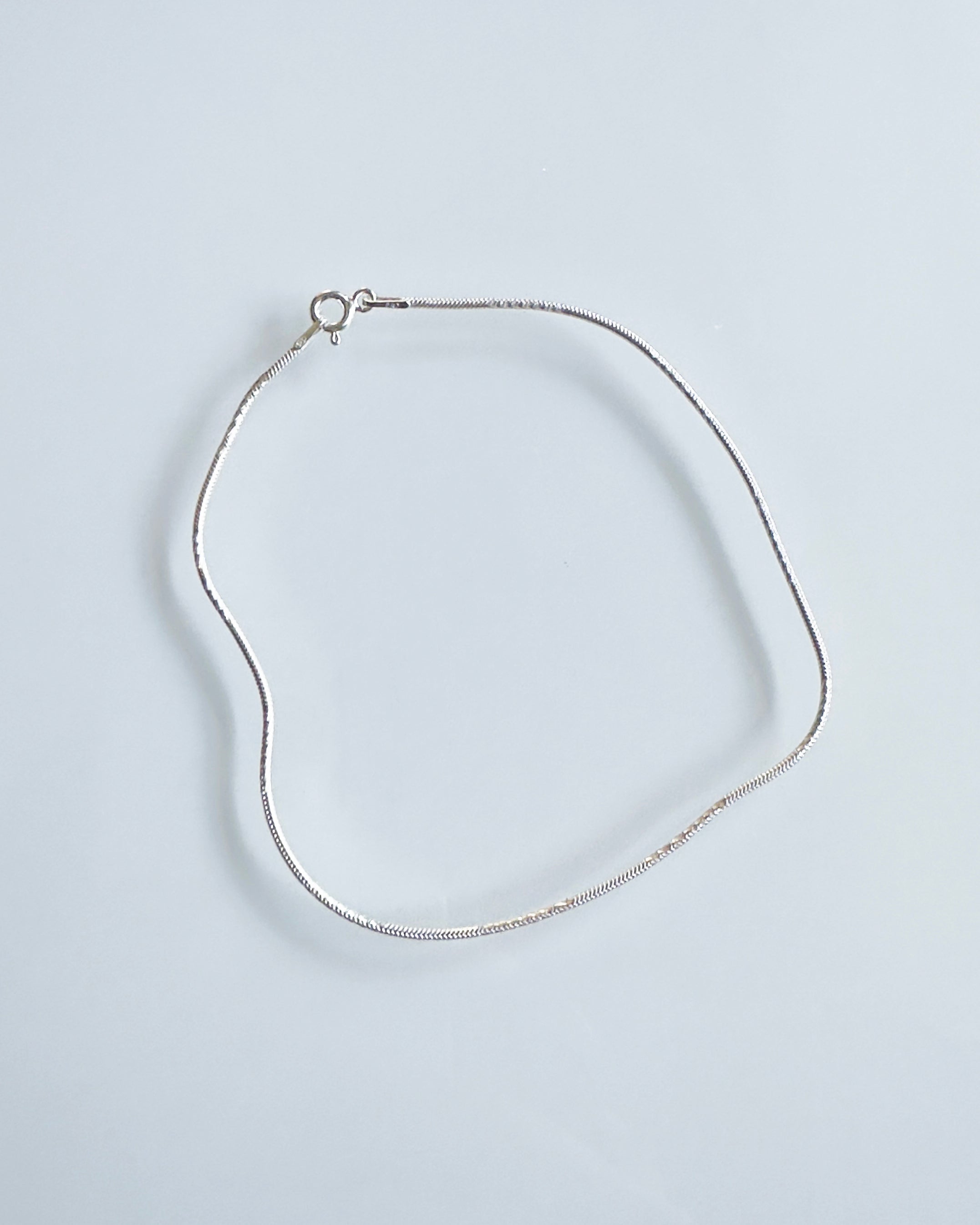 Silver anklet on a light gray background