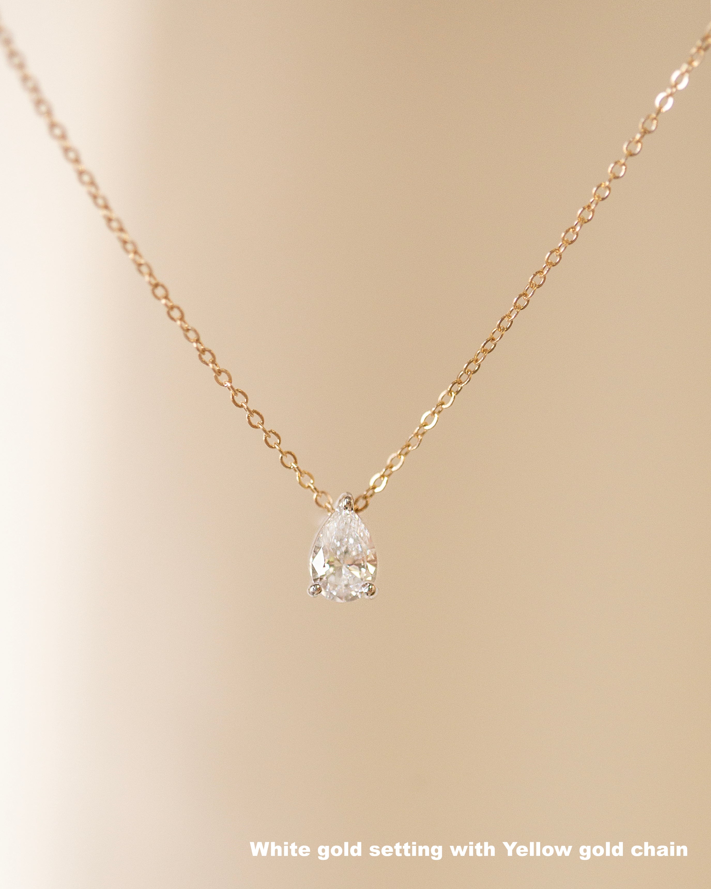 Gold necklace with a white gold setting on a beige background