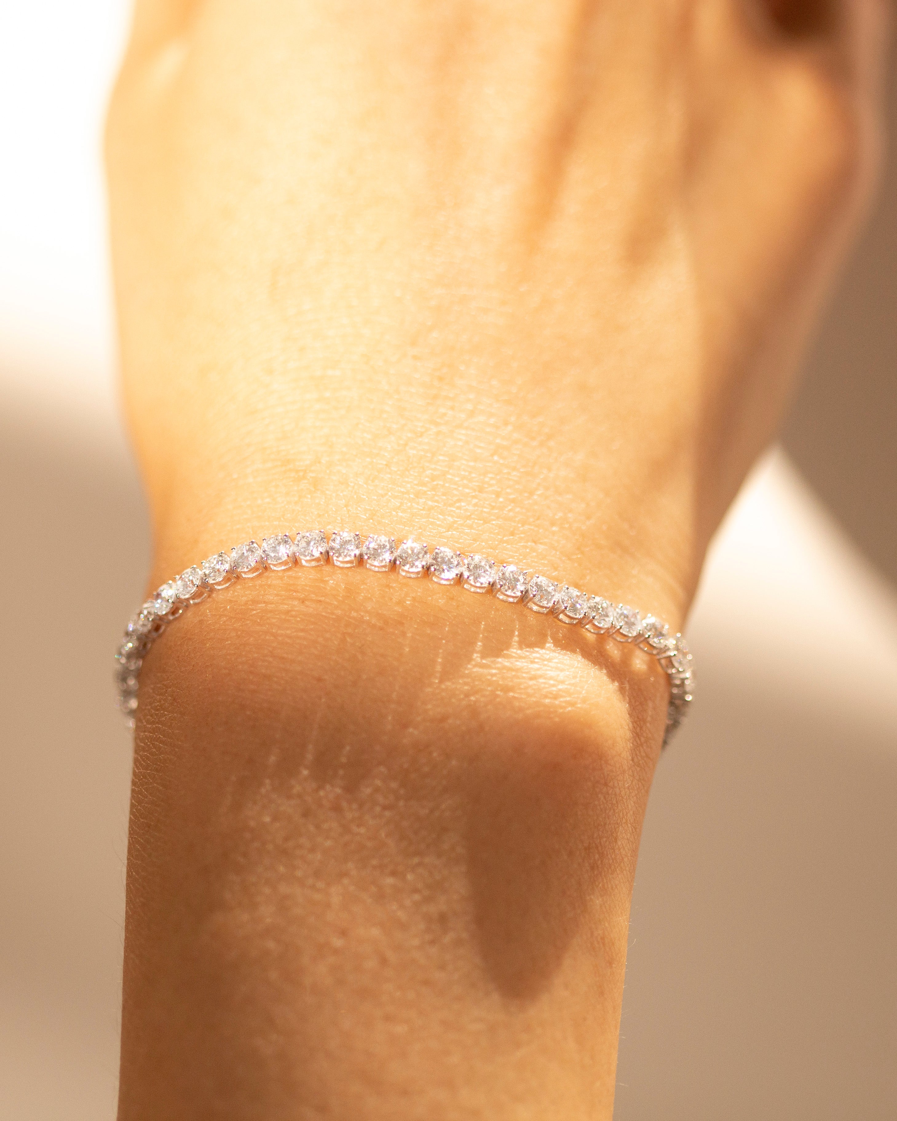diamond tennis bracelet on a wrist with a blurred background 
