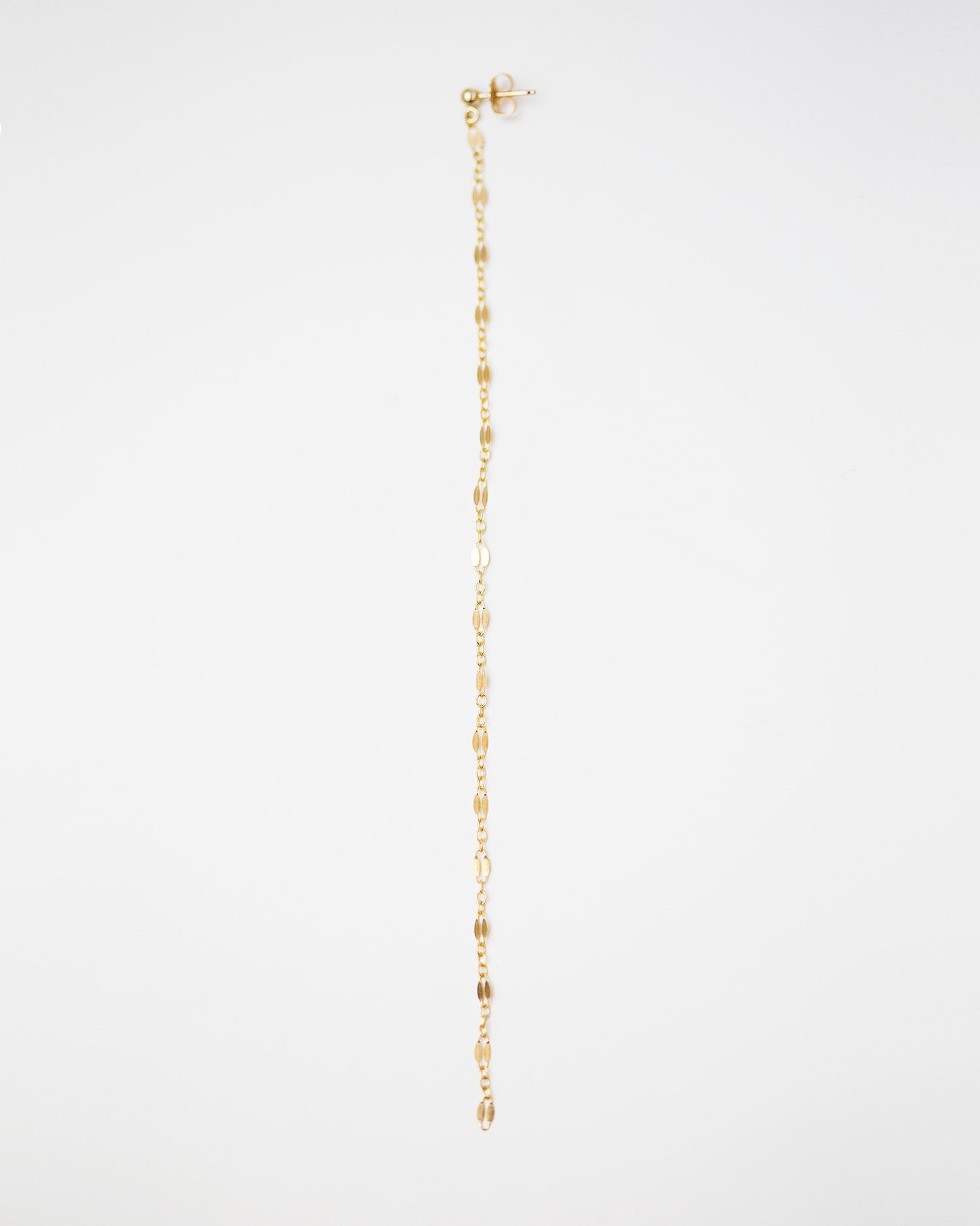 Pretty gold chain hangs from a gold ball stud