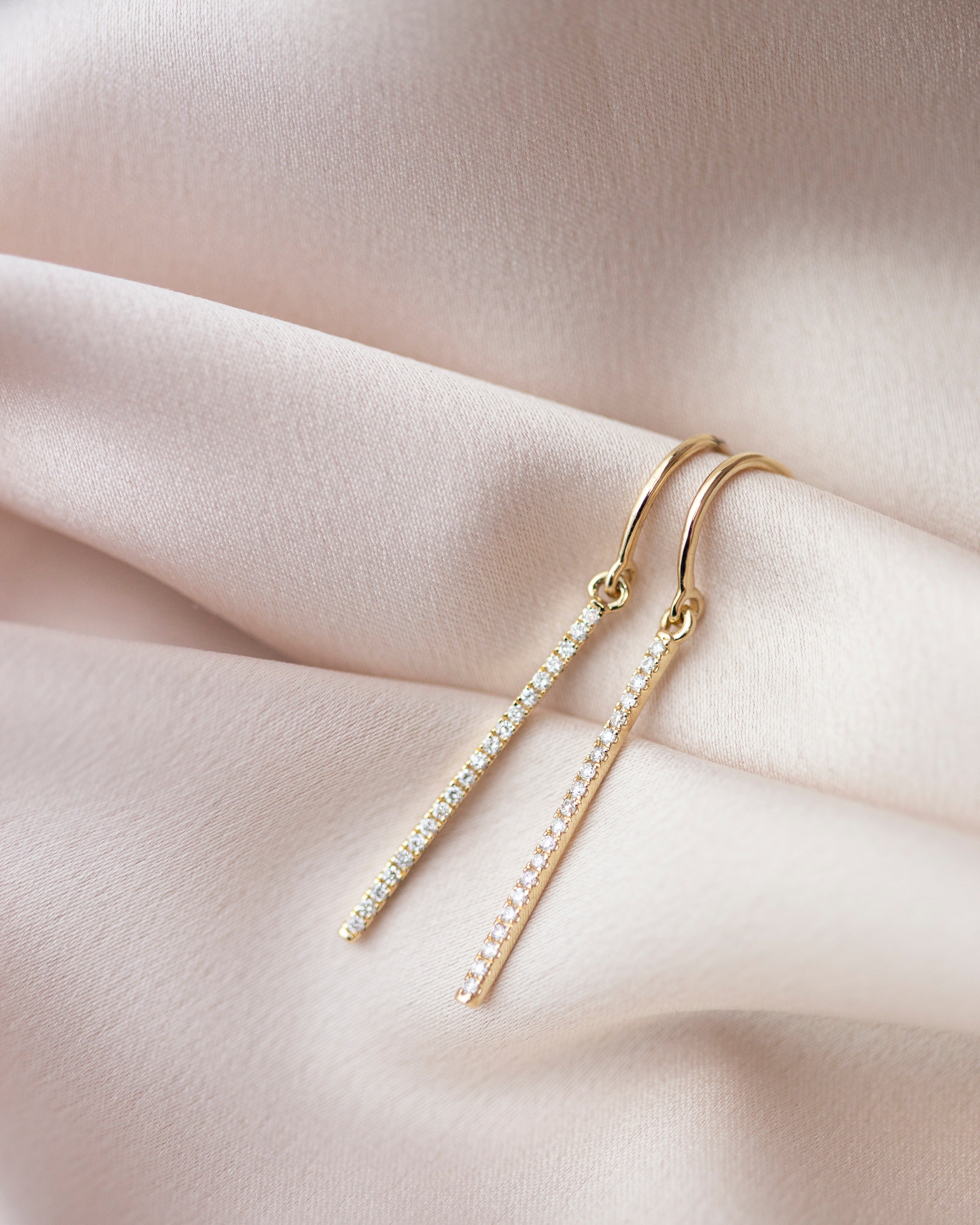 These exquisite 14k gold drop bar earrings feature genuine diamonds, adding a modern touch to their versatile design. A must-have for those seeking a timeless and sophisticated accessory.
