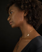 A gold chain necklace with two small heart pendants.