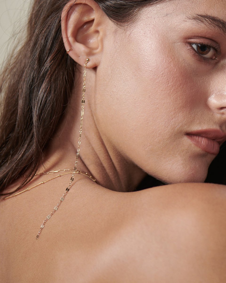 Pretty gold chain hangs from a gold ball stud