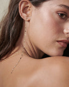 Pretty gold chain hangs from a gold ball stud